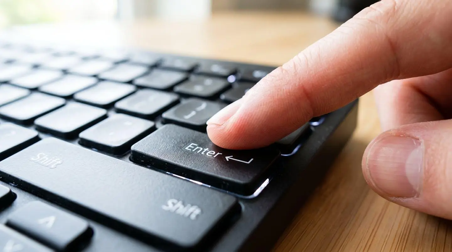 Gros plan extrême sur un doigt appuyant sur la touche Entrée d'un clavier d'ordinateur moderne, faible profondeur de champ, lumière naturelle vive